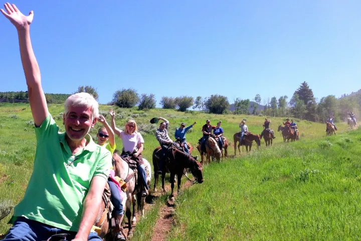 a group of people riding on the back of a horse in a field